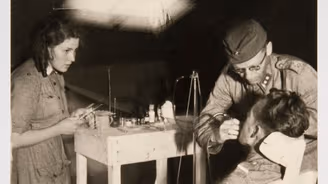 Museoviraston kuvassa lääkintäluutnantti hoitaa suomalaiskorpraalin kipeytynyttä hammasta Pohjois-Suomen rintamalla jatkosodassa kesällä 1941.