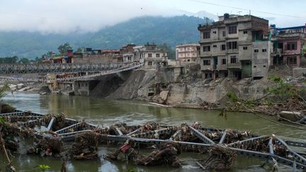 Les vestiges d'un pont emporté par les eaux de crue gisent dans la rivière, à Devighat, dans le district de Nuwakot, au Népal, le 15 octobre 2026. (SUNIL PRADHAN / ANADOLU / AFP)