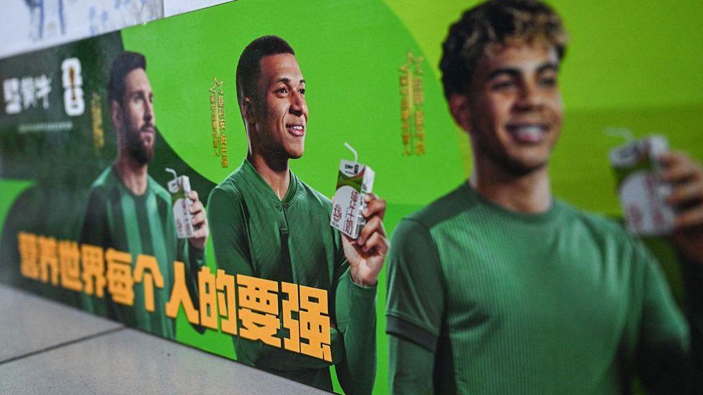 This photo shows an advertising campaign for Chinese dairy brand 'Mengniu' featuring football stars France's Kylian Mbappe (C), Argentina's Lionel Messi (L) and Spain's Lamine Yamal at a supermarket in Beijing on October 28, 2026